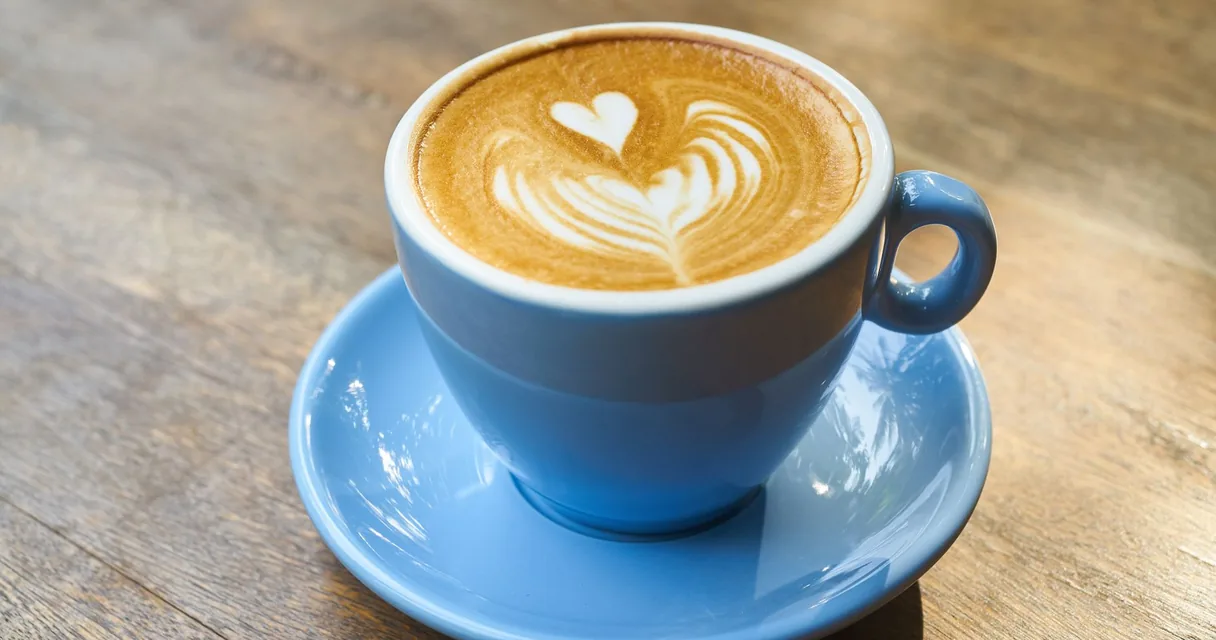 Xícara de café com espuma sobre pires azul