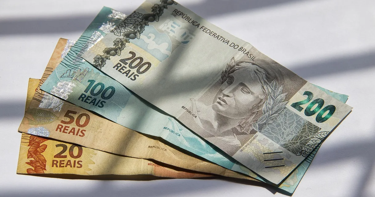 Notas de 20, 50, 100 e 200 reais sobre uma mesa, ilustrando o custo de IPTV 20 reais
