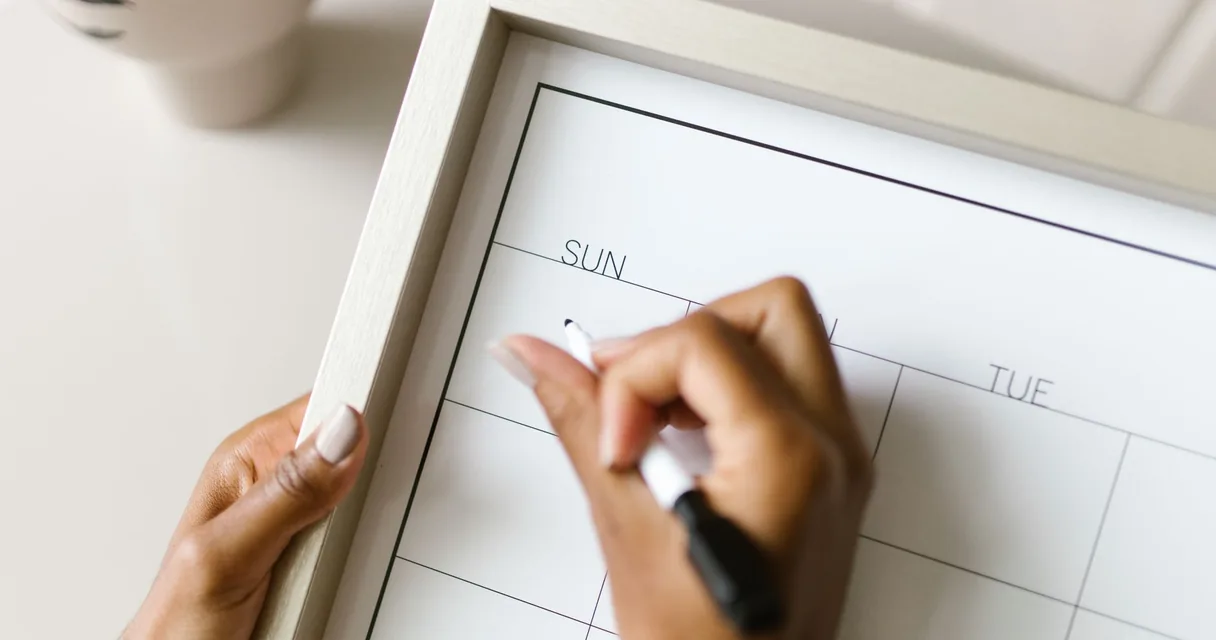 Mãos escrevendo em um calendário de parede para marcar os dias do teste de IPTV 30 dias grátis