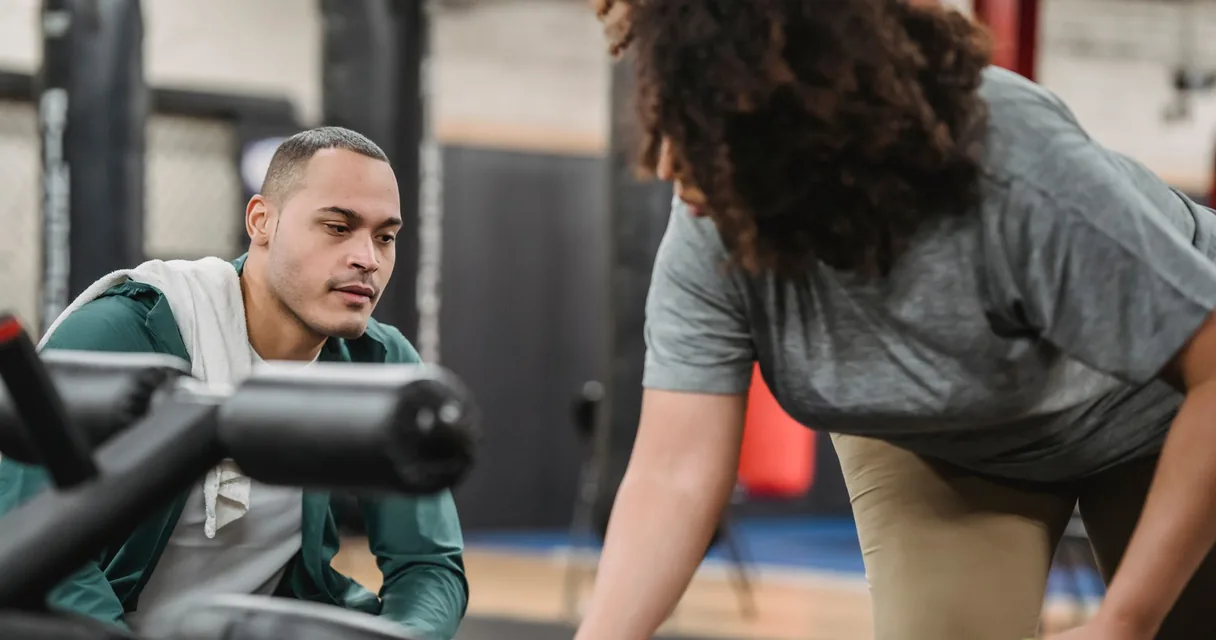 Personal trainer orientando aluna durante treino na academia